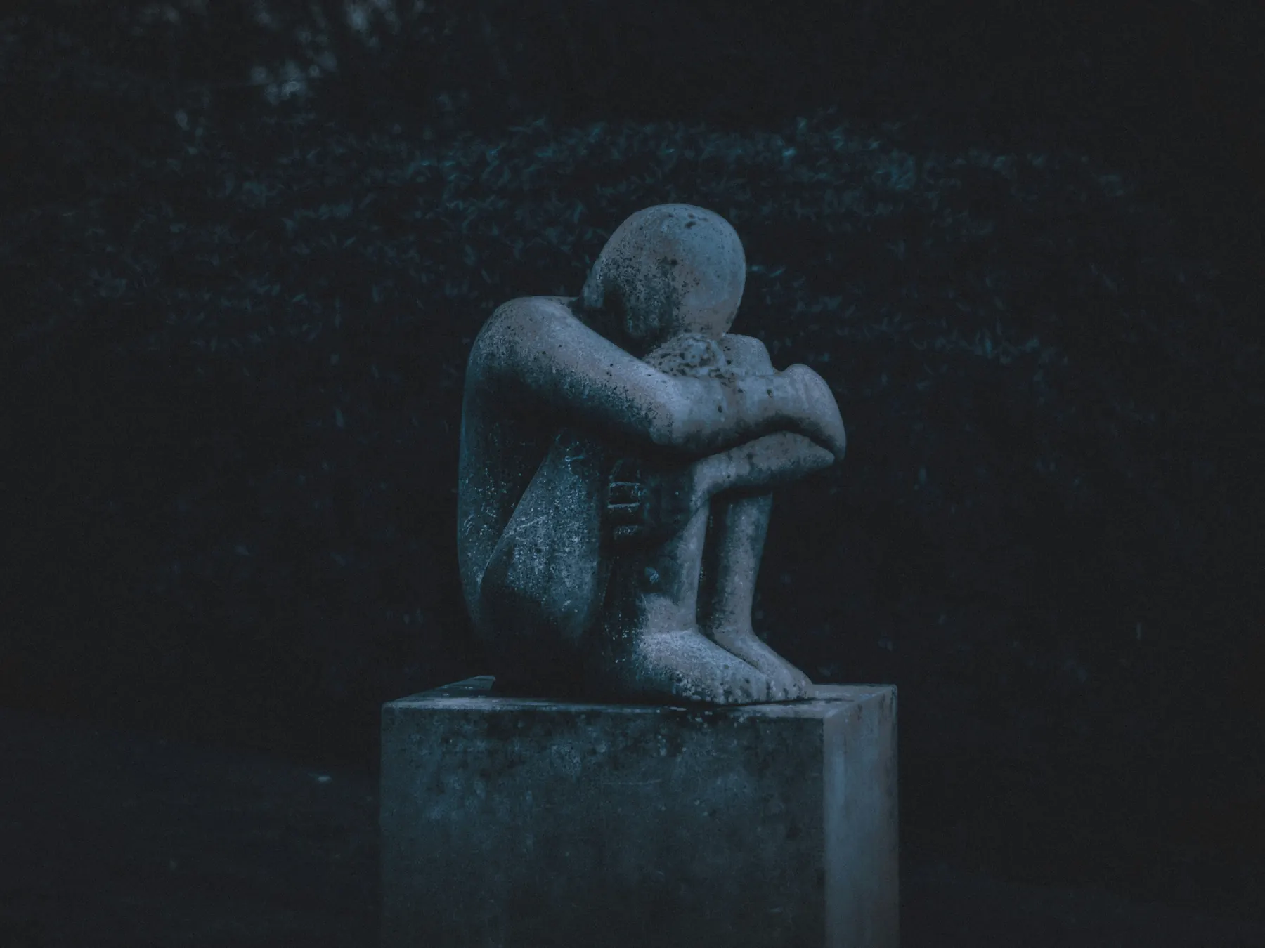 Escultura de una figura encogida sobre sí misma